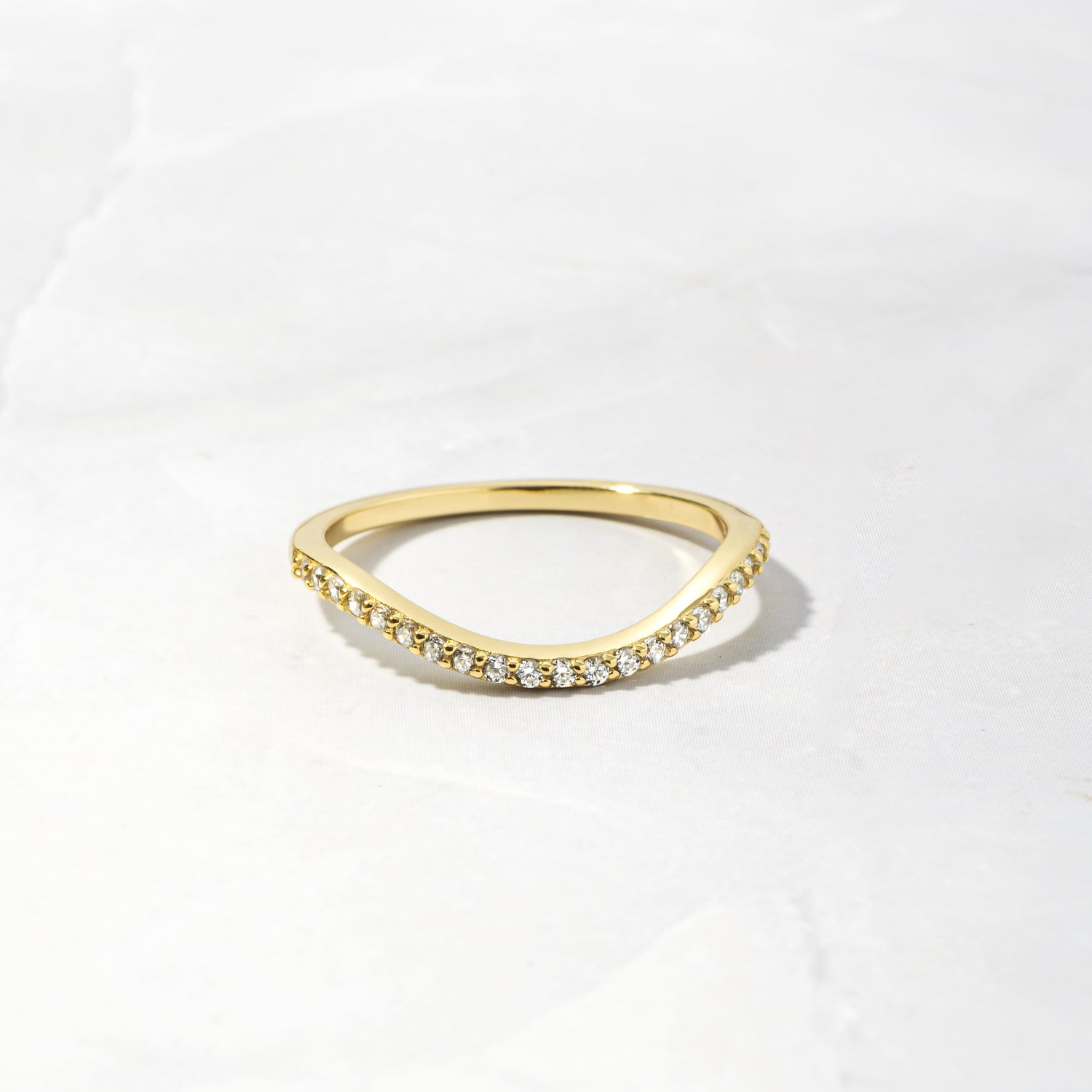 A gold curved band as part of a toi et moi wedding band ring set on a white background