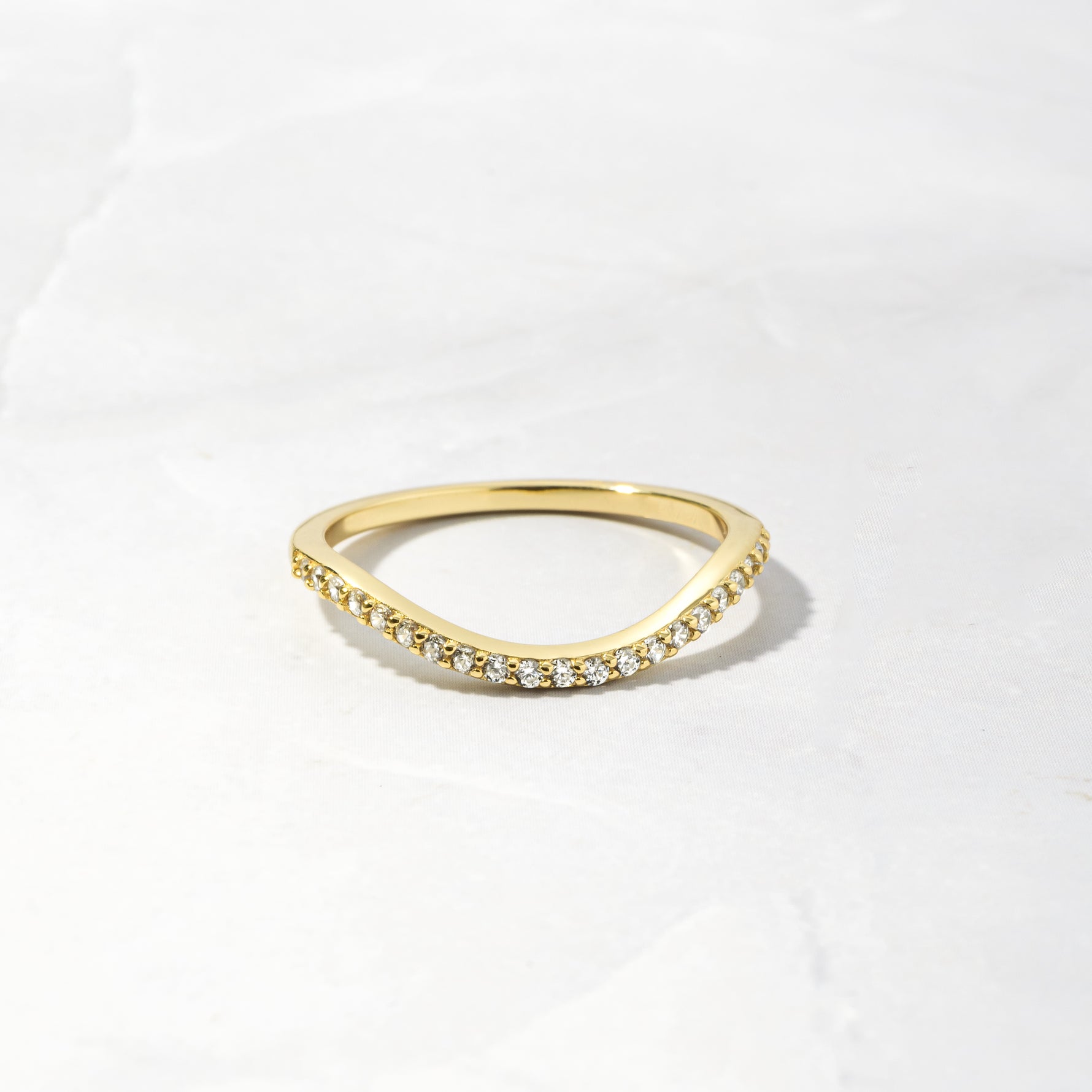 A gold curved band as part of a toi et moi wedding band ring set on a white background