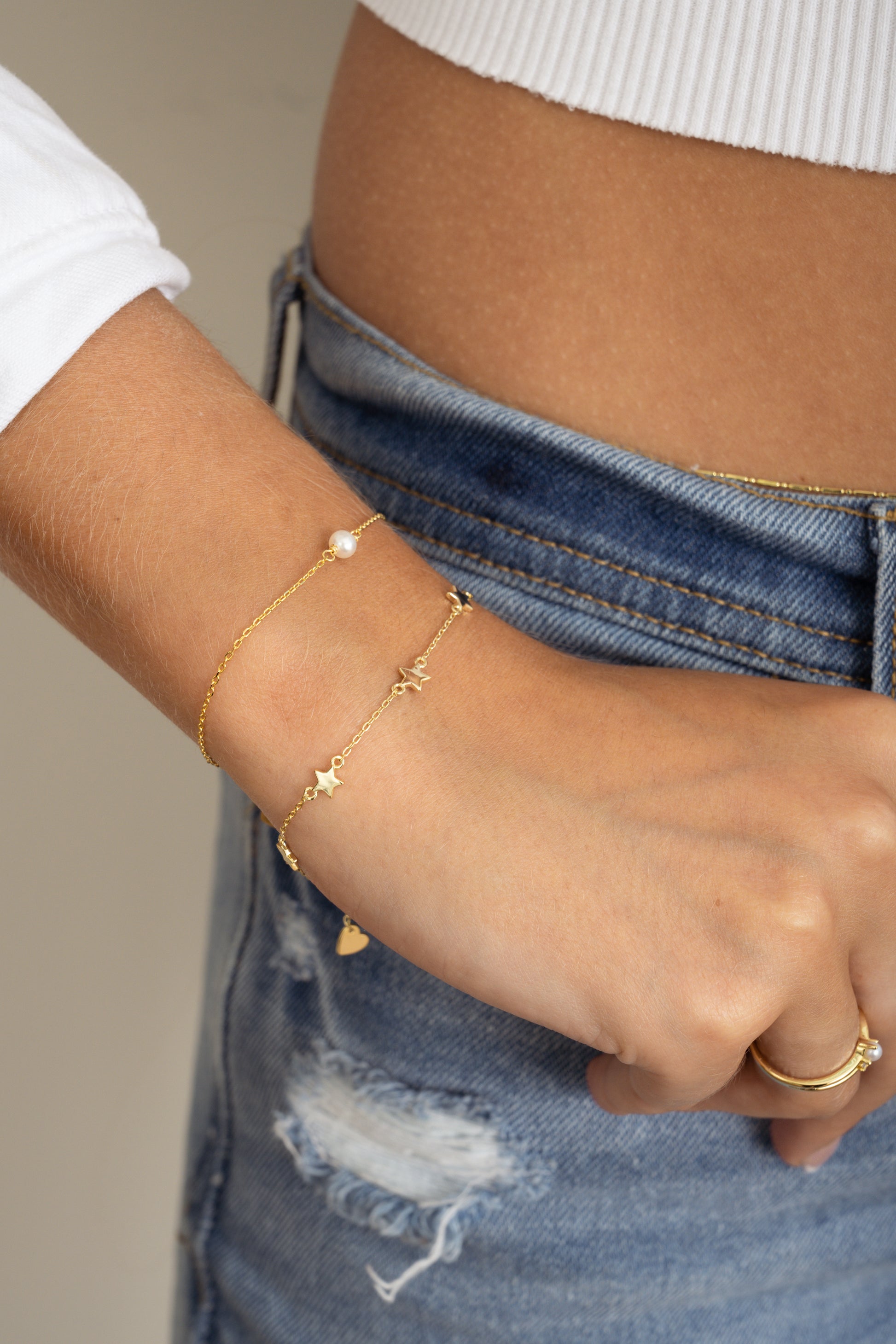 model wearing dainty stacking bracelets of a pearl and a star bracelet