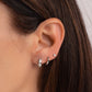 Close up of model wearing small silver huggie earrings featuring a diamond stripe in the center in her first piercing, and then a small huggie hoop earrings on her second piercing and a silver tiny diamond stud in her third piercing