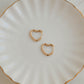 Minimalist gold heart earring hoops for her on white jewelry dish