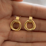 close up of a refined yet modern pair of gold Knot Hoops, held on hand