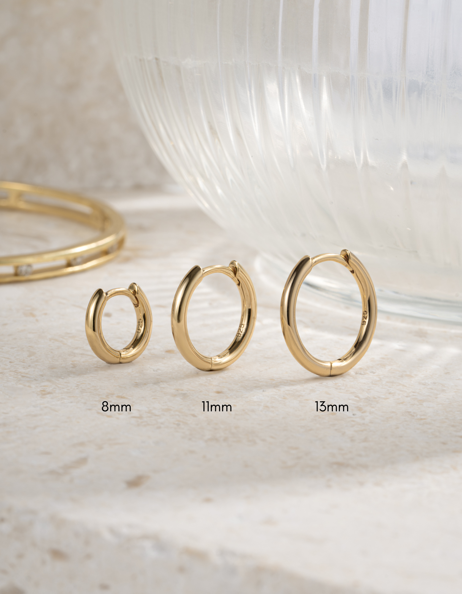 Gold 8mm hoop earrings, 11mm hoop earrings and 13mm hoop earrings on a light background