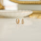 Dainty diamond huggie earrings in 14k gold plated finish on white marble