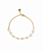A delicate gold chain bracelet featuring a row of pear-cut cubic zirconia stones in a gold setting, with a small gold heart charm at the clasp, shown on a plain white background.