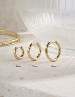 Three small gold hoop earrings from Sami Jewels featuring minimalist design in a set of different sizes.