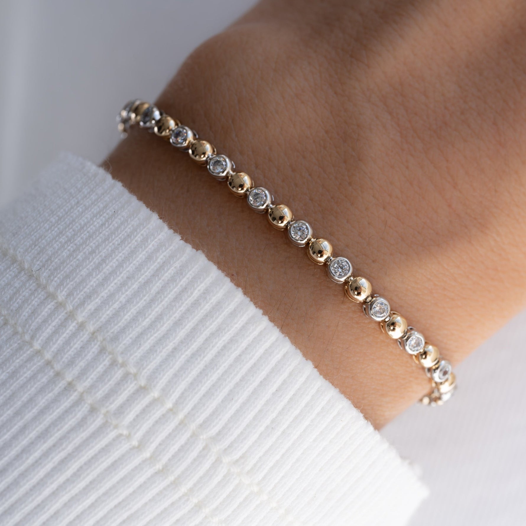 Close-up of a dainty bezel tennis bracelet, worn by the model