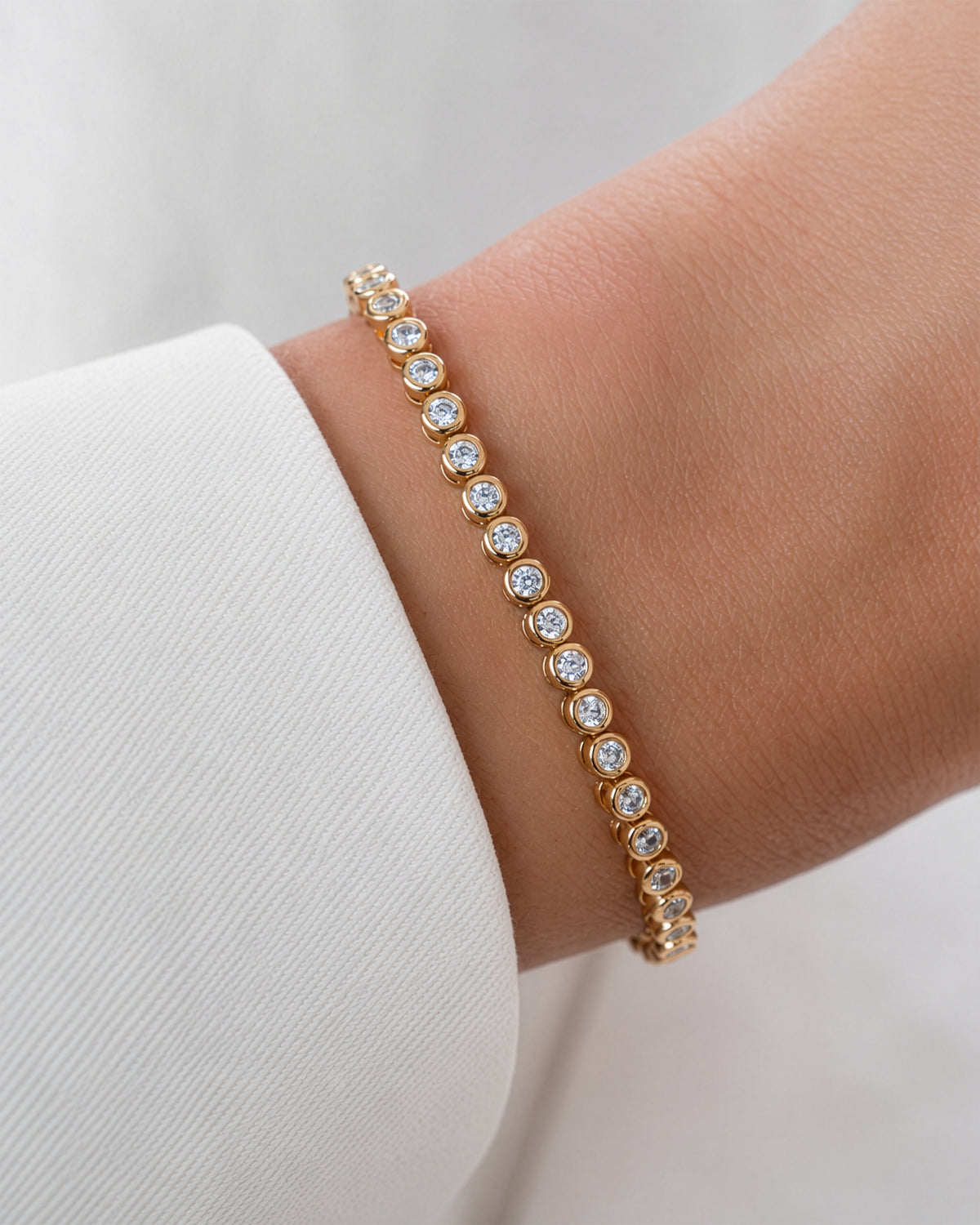 Moissanite round bezel tennis bracelet in gold vermeil worn alone on the wrist
