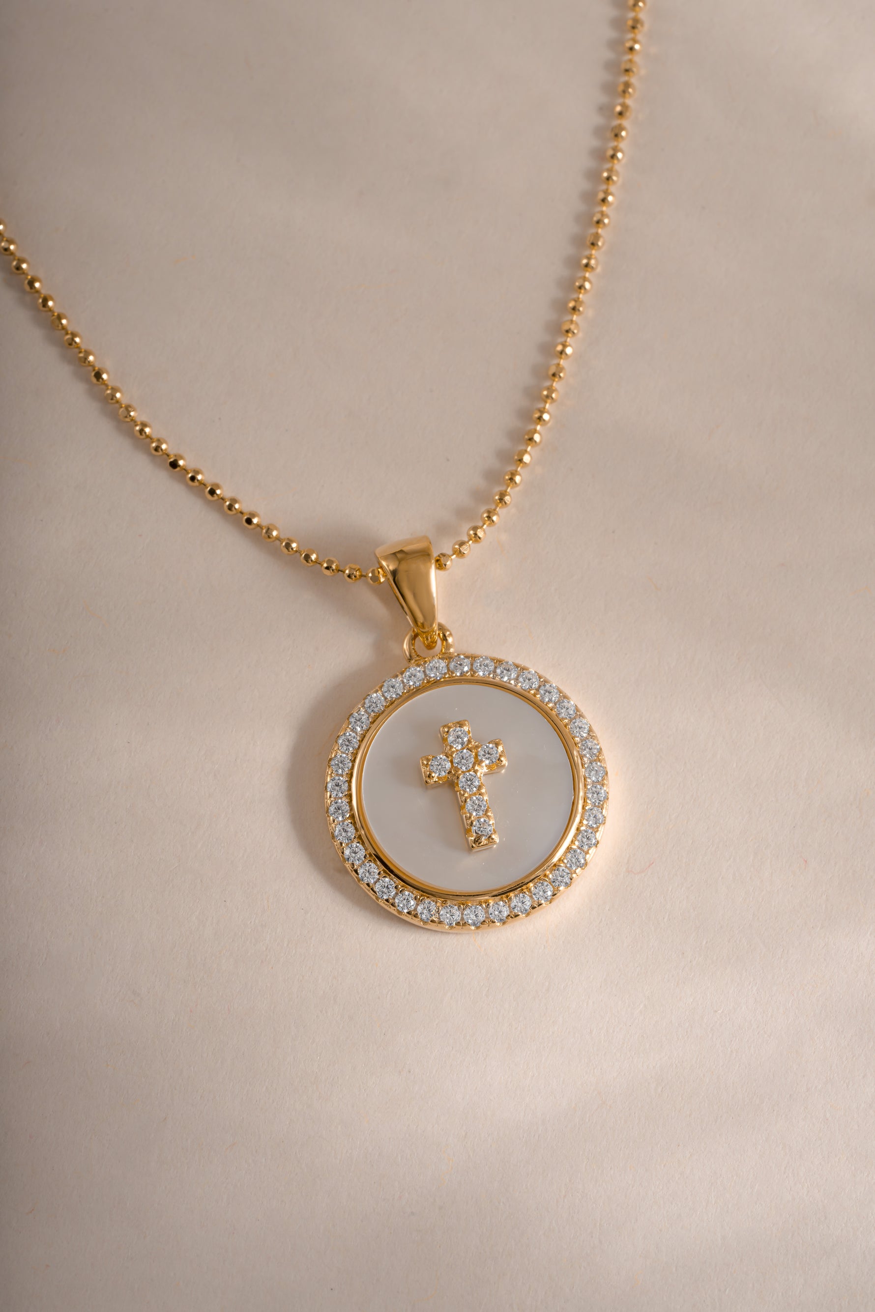 Close-up of Sami Jewels mother of pearl cross necklace in gold, showcasing intricate design and polished surface.