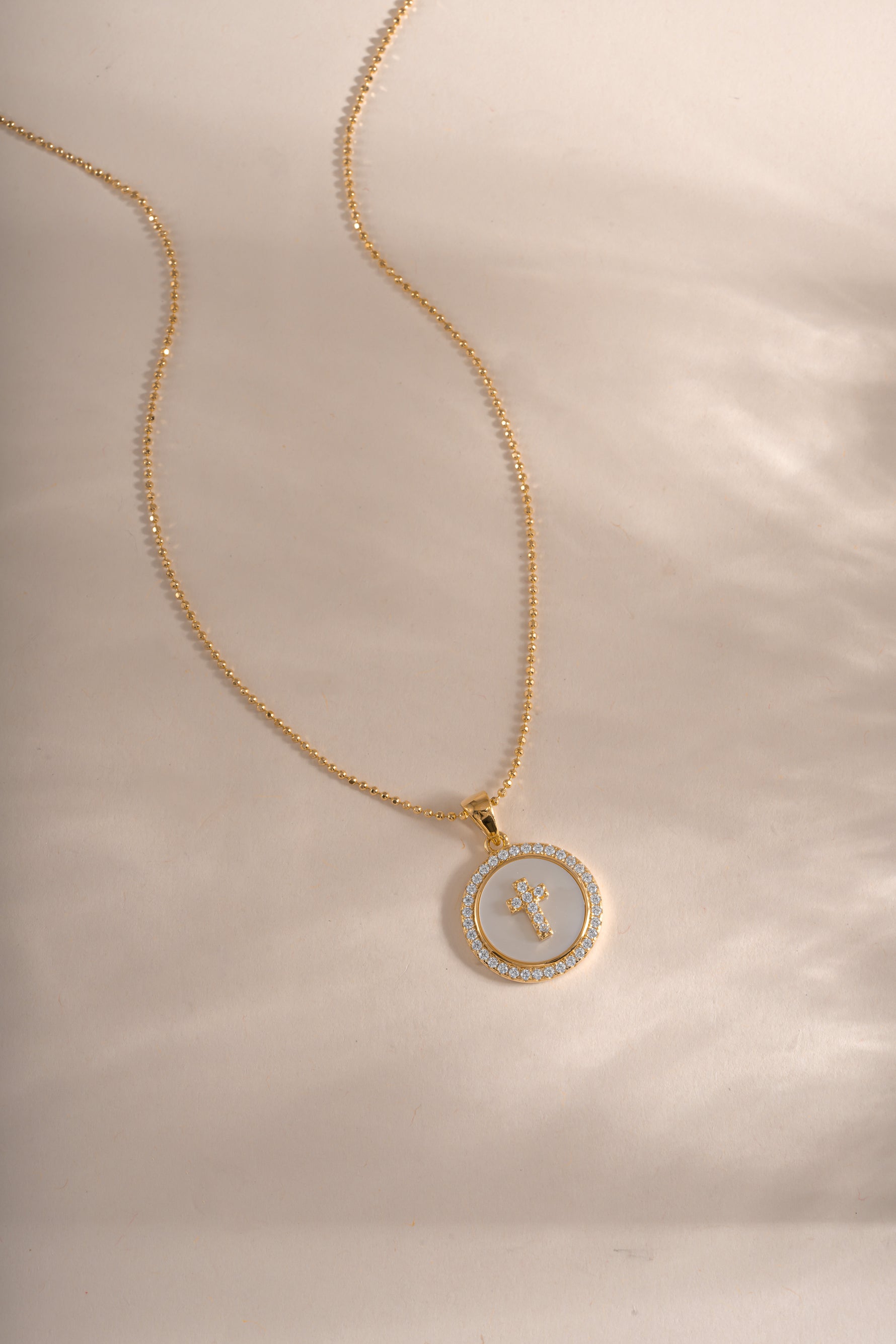 Sami Jewels mother of pearl cross necklace with a delicate pendant on a silver chain, showcasing elegant jewelry design.