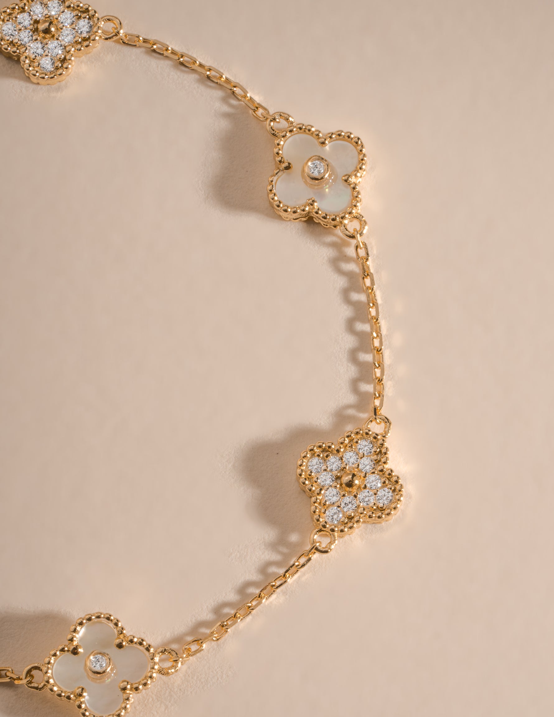 Gold bracelet with a four-leaf clover charm featuring mother-of-pearl and cubic zirconia details by Sami Jewels.