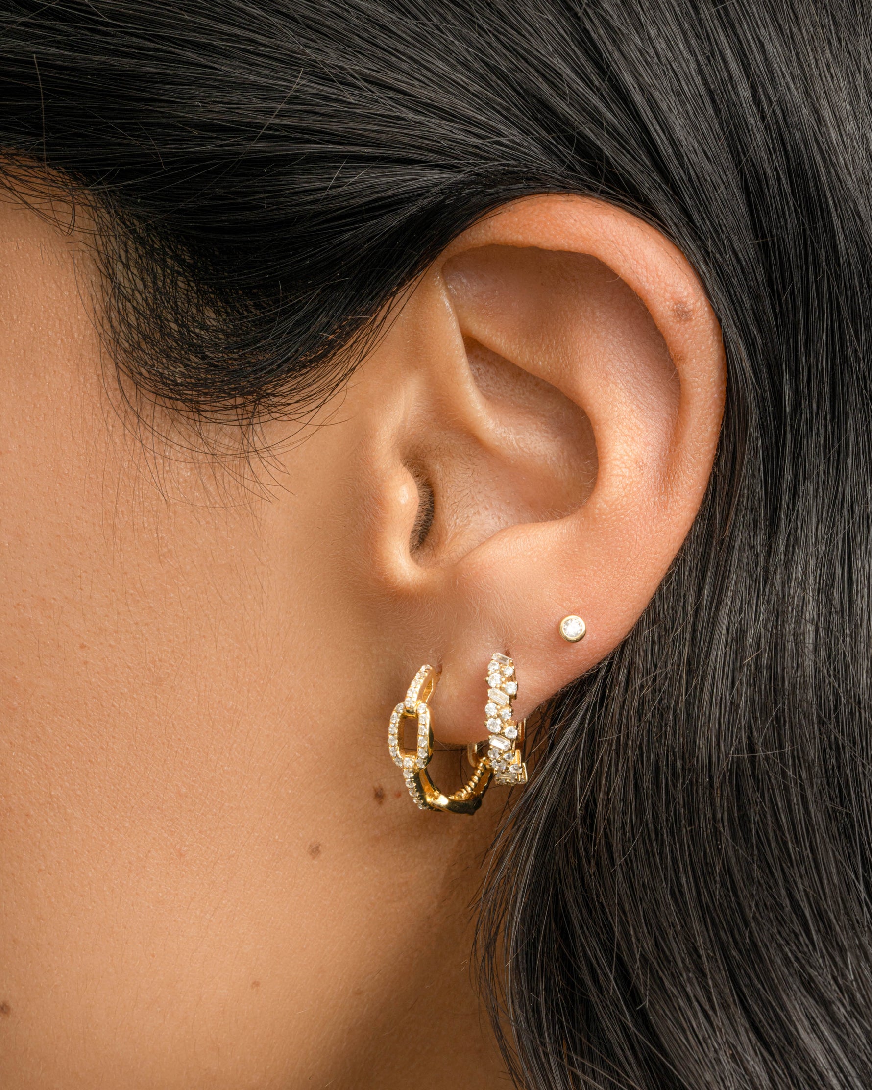 Gold multi-stone diamond huggie hoop earrings by Sami Jewels featuring colorful gemstone accents and a sleek hoop design.