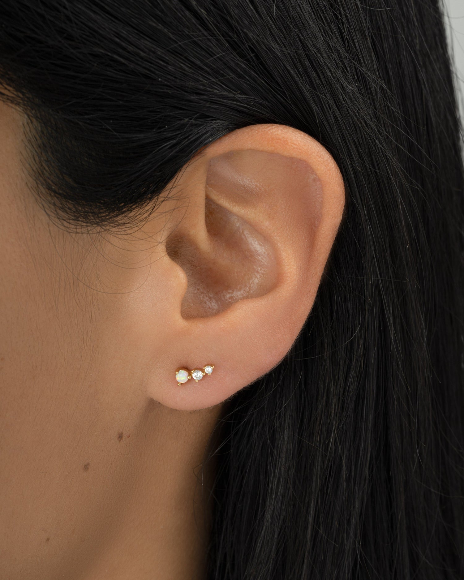 Gold opal ear climber earrings by Sami Jewels displayed on a model, showcasing elegant curved design and vibrant opal stones.