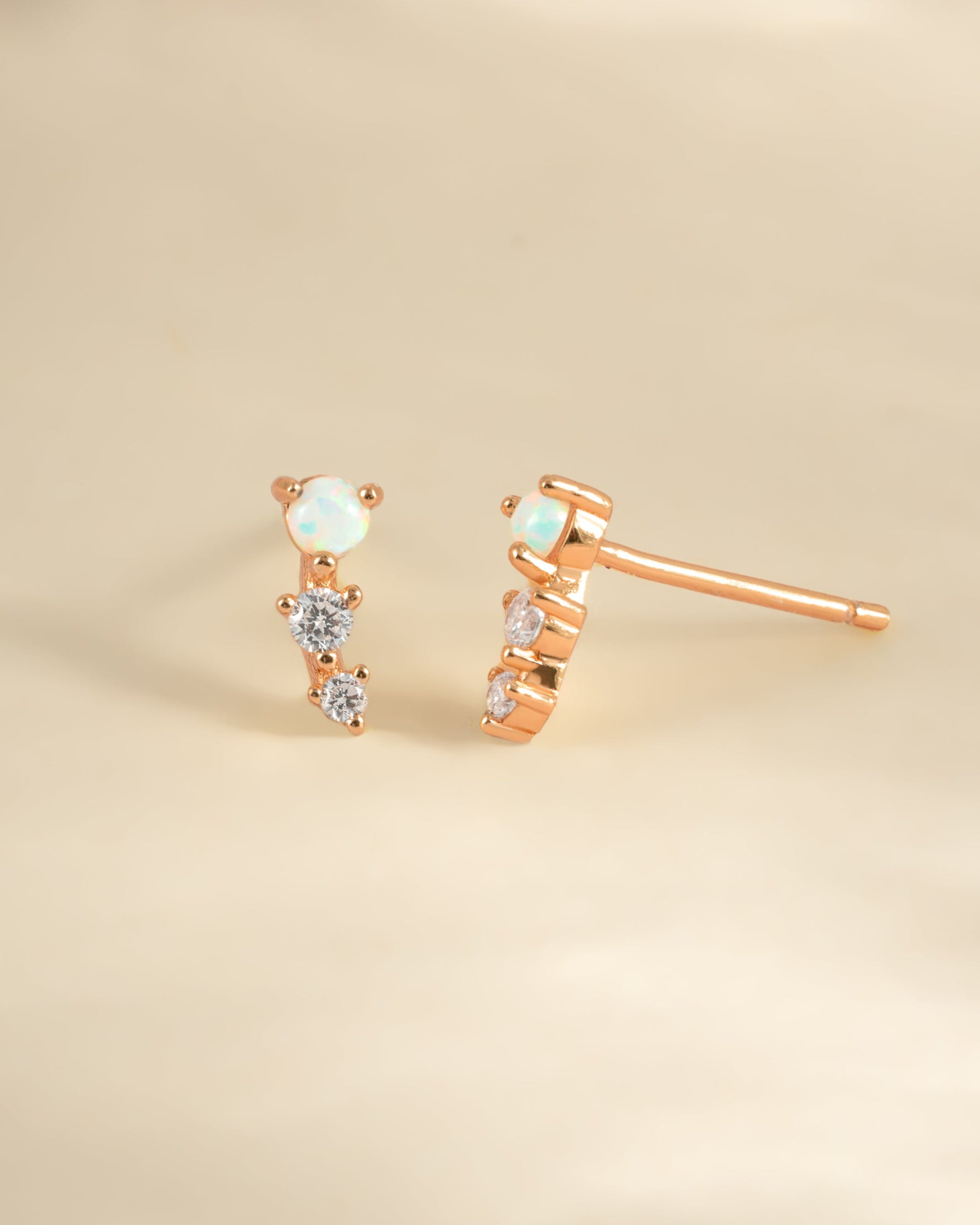 Rose gold opal ear climber earrings by Sami Jewels, featuring sparkling opal stones and elegant curved design.