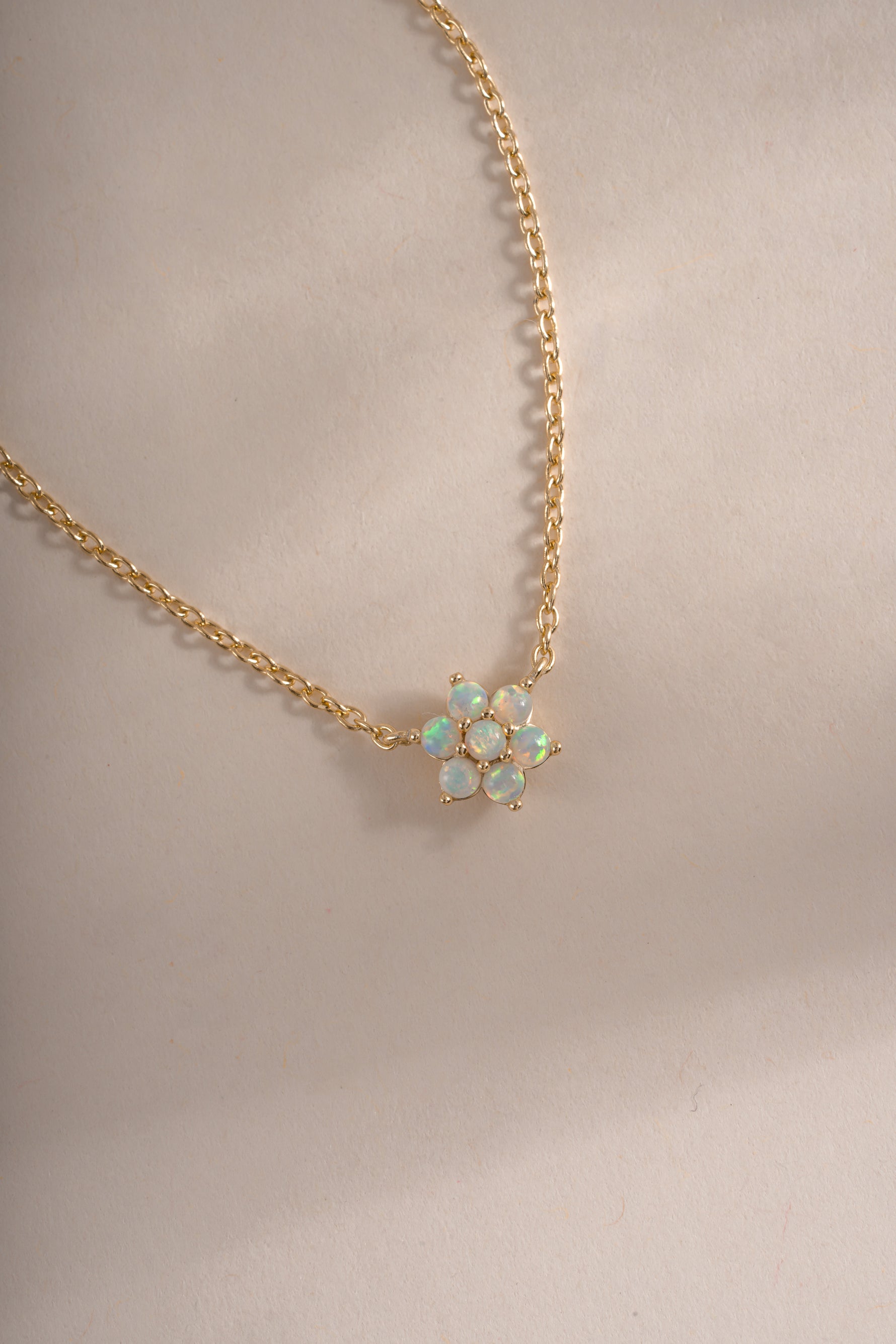 Close-up of Sami Jewels opal flower necklace featuring a gold chain and blooming flower design.