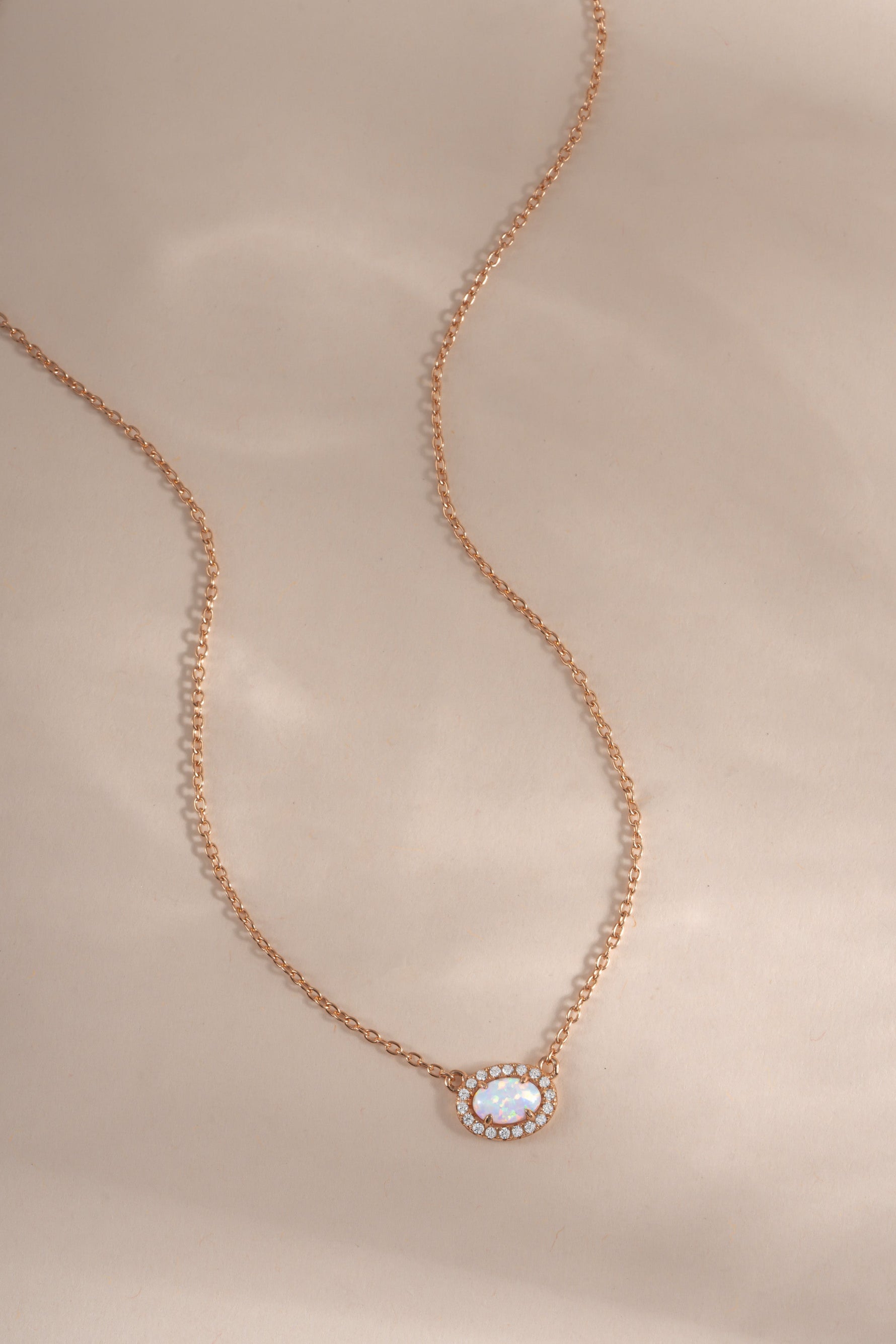 Rose gold Opal Halo Necklace by Sami Jewels with a central opal gemstone surrounded by a halo setting.