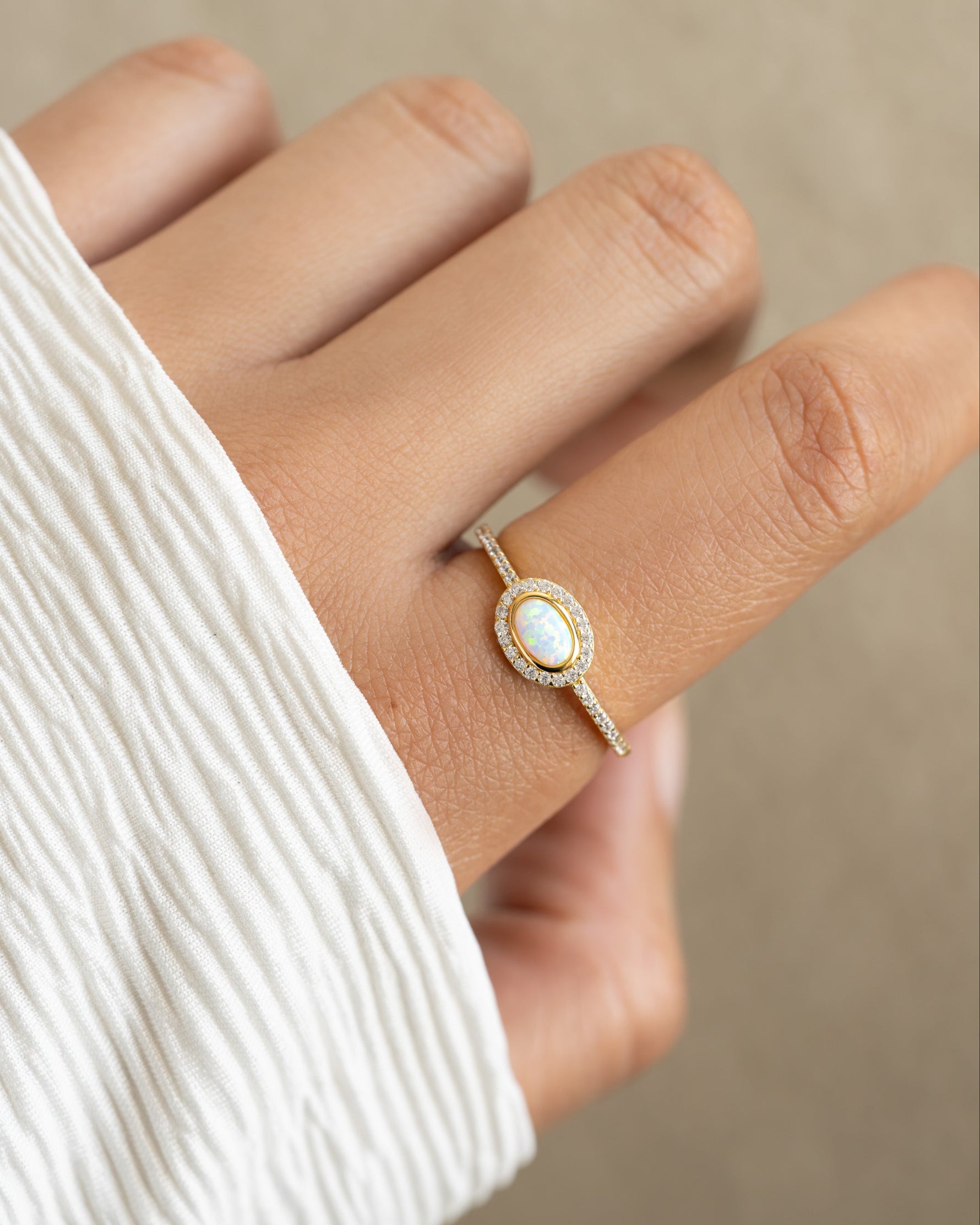 Gold opal halo ring by Sami Jewels featuring a vibrant, iridescent opal gemstone surrounded by a delicate halo setting.