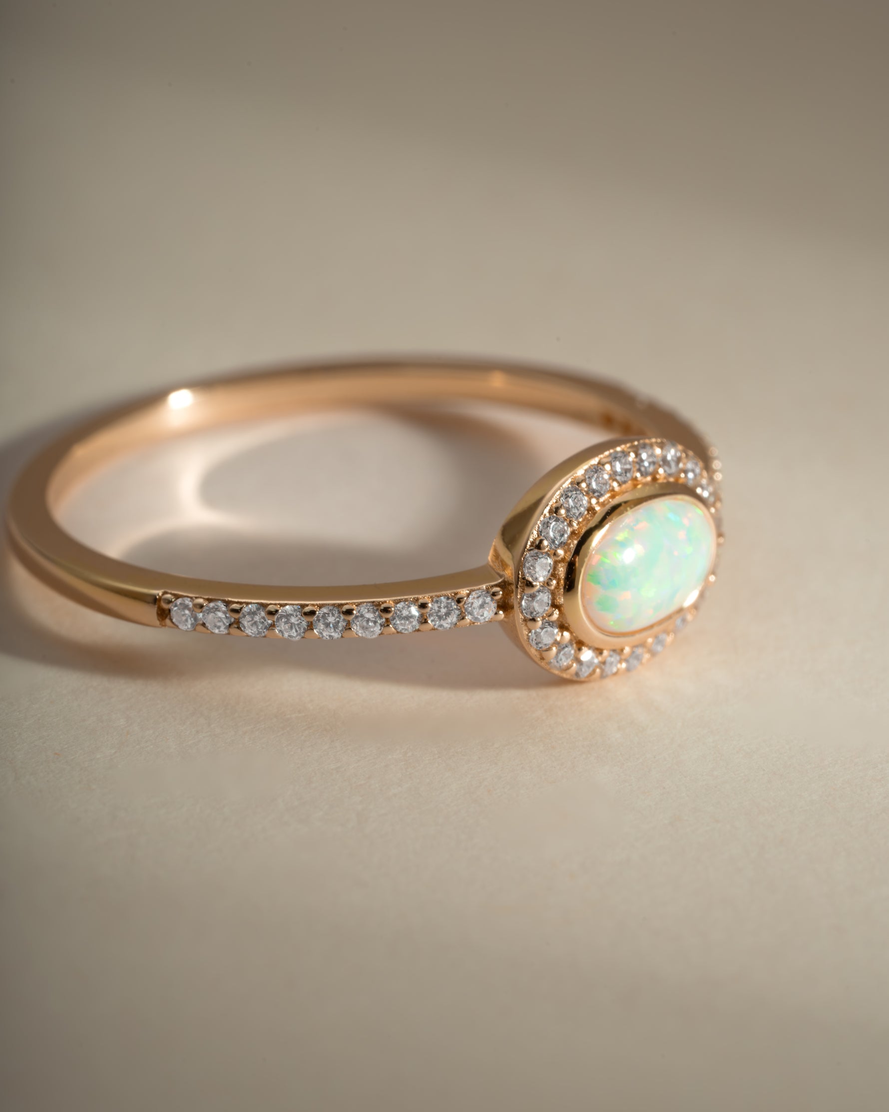 Sami Jewels opal halo ring with gold band, side view showing the shimmering opal centerpiece and detailed setting.