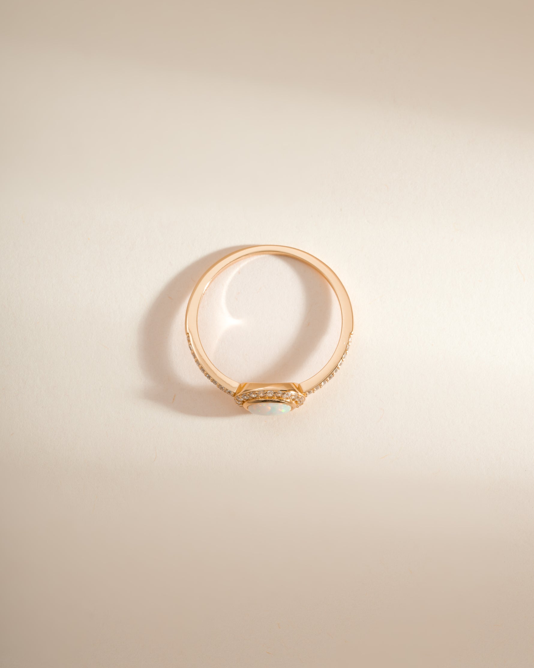 Gold opal halo ring by Sami Jewels, top view showing the vibrant opal gemstone surrounded by a delicate halo design.