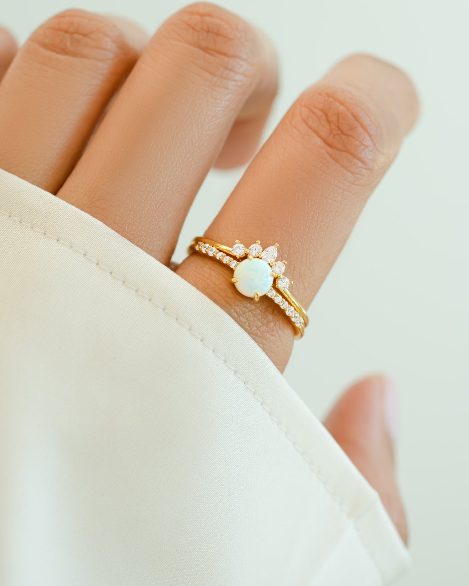 Gold opal ring set with pave ring from Sami Jewels, featuring multiple rings with sparkling opal stones on a model's hand.