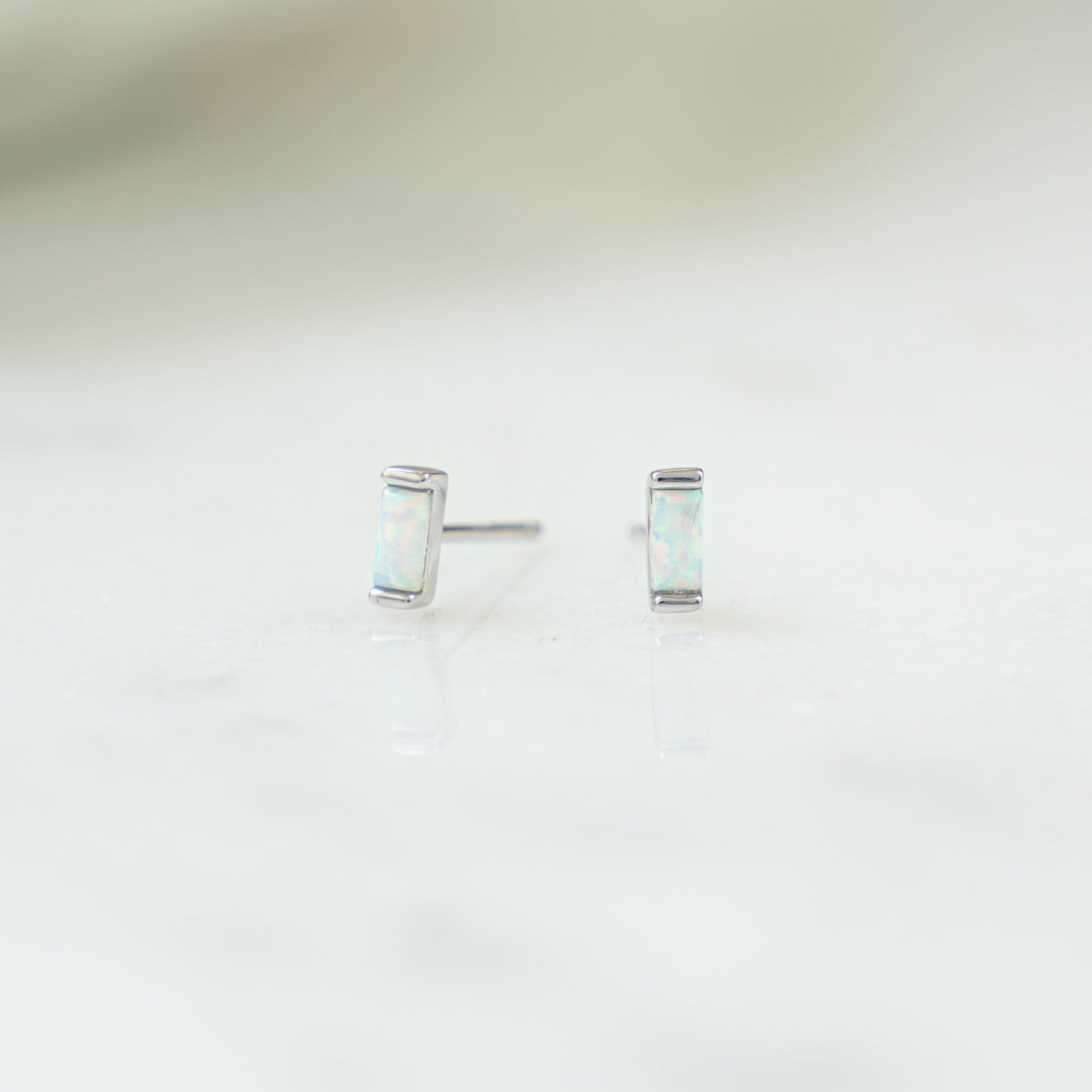 closeup image of silver stud earrings with opal gemstone 