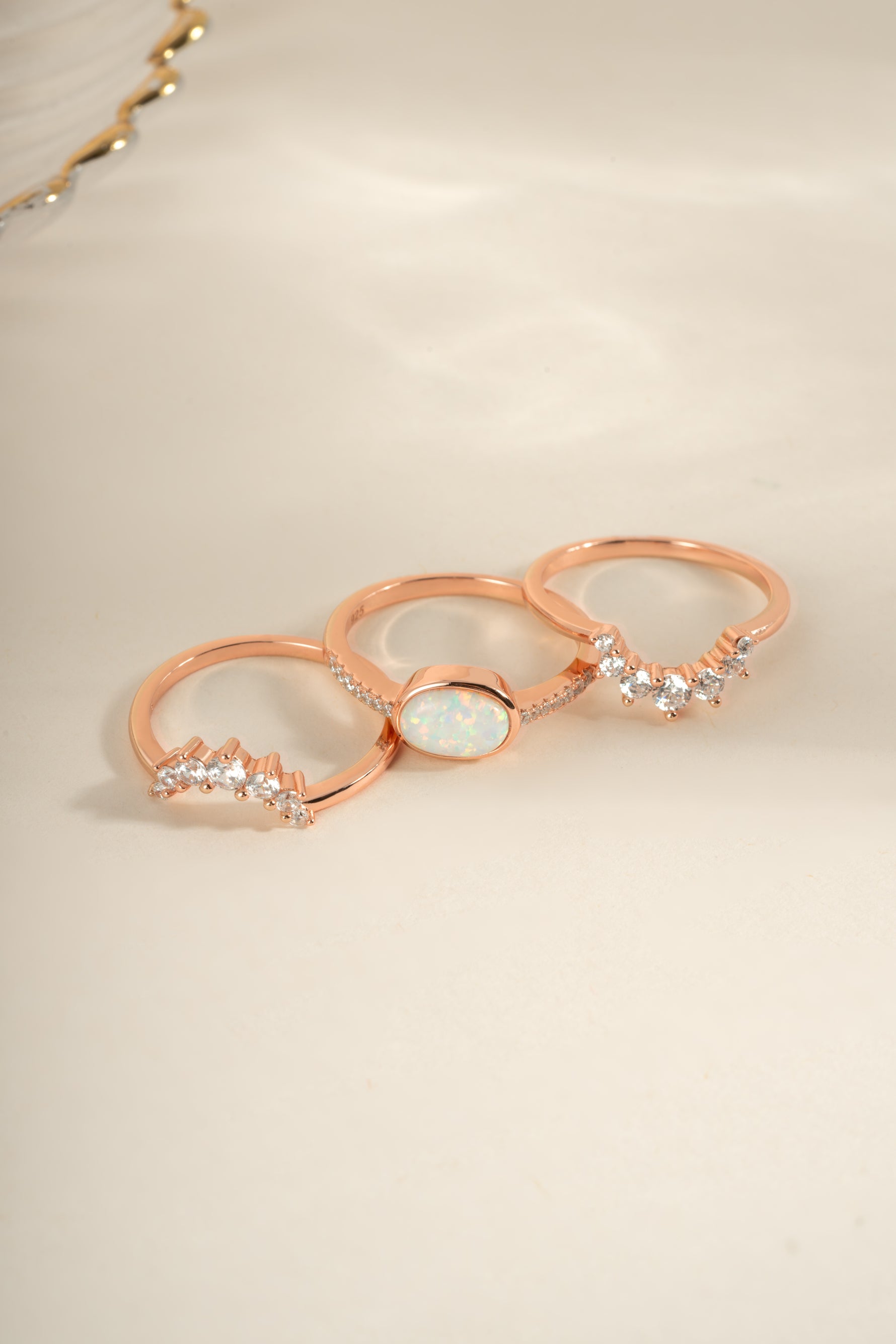 Three Sami Jewels opal rings set in rose gold, displayed from an angled view showcasing the colorful opal stones.
