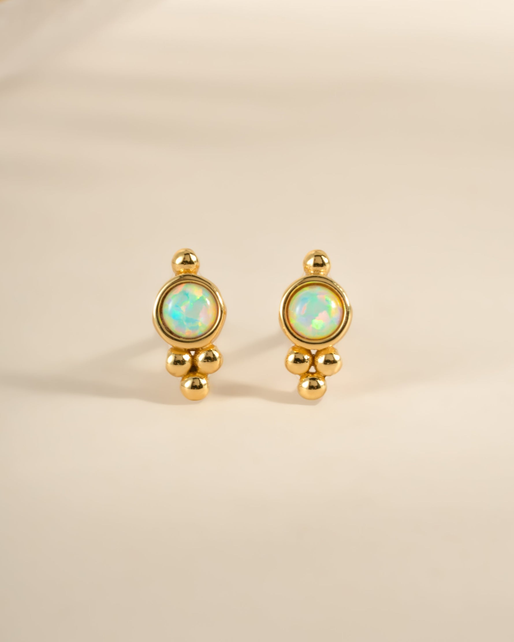 Gold embellished opal stud earrings by Sami Jewels, featuring round opals with decorative gold accents, front view.
