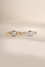 Product image of gold and silver sideways oval bezel ring side by side.