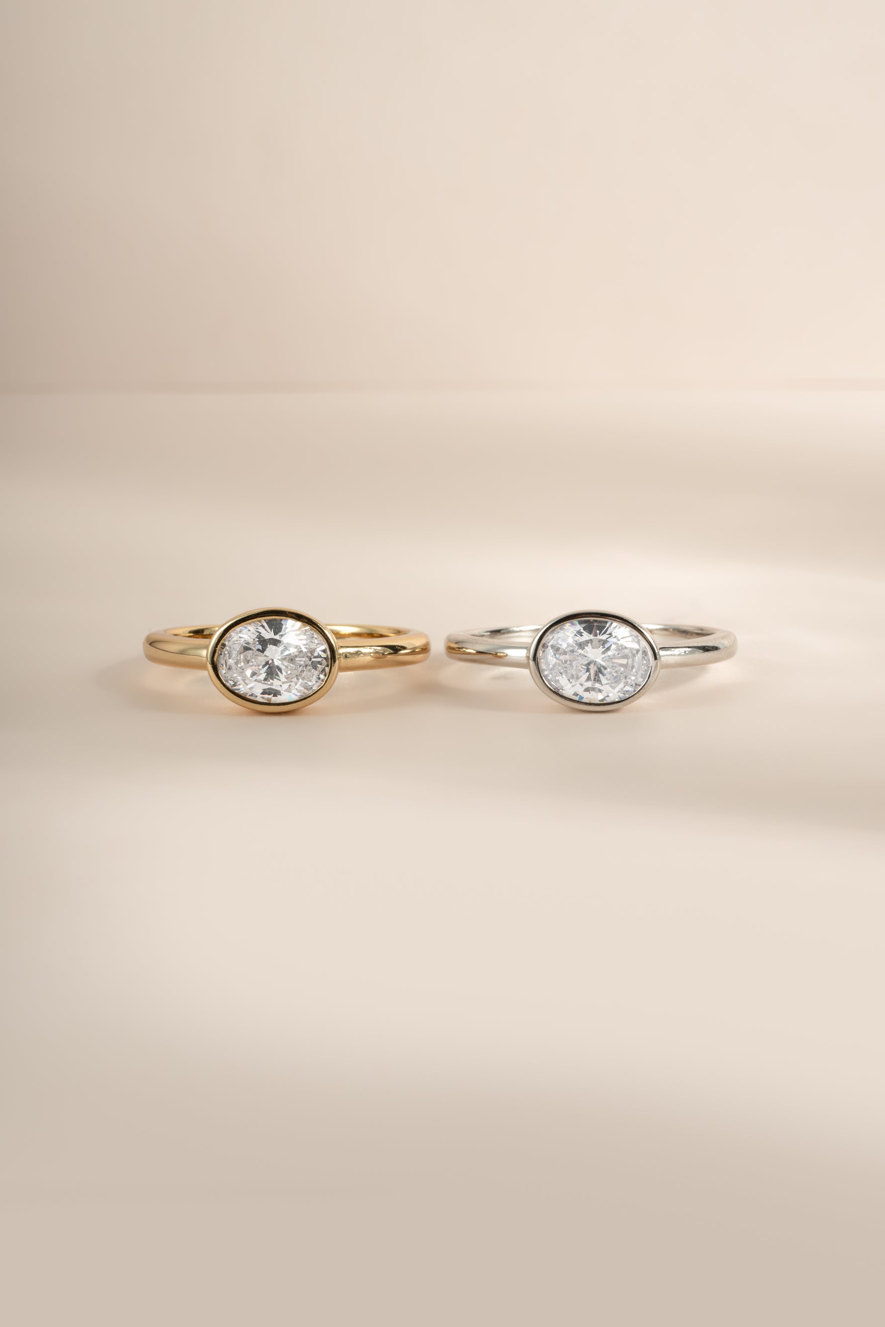 Product image of gold and silver sideways oval bezel ring side by side.
