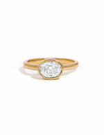 A yellow gold ring with a bezel-set oval cubic zirconia stone photographed on a clean white background.