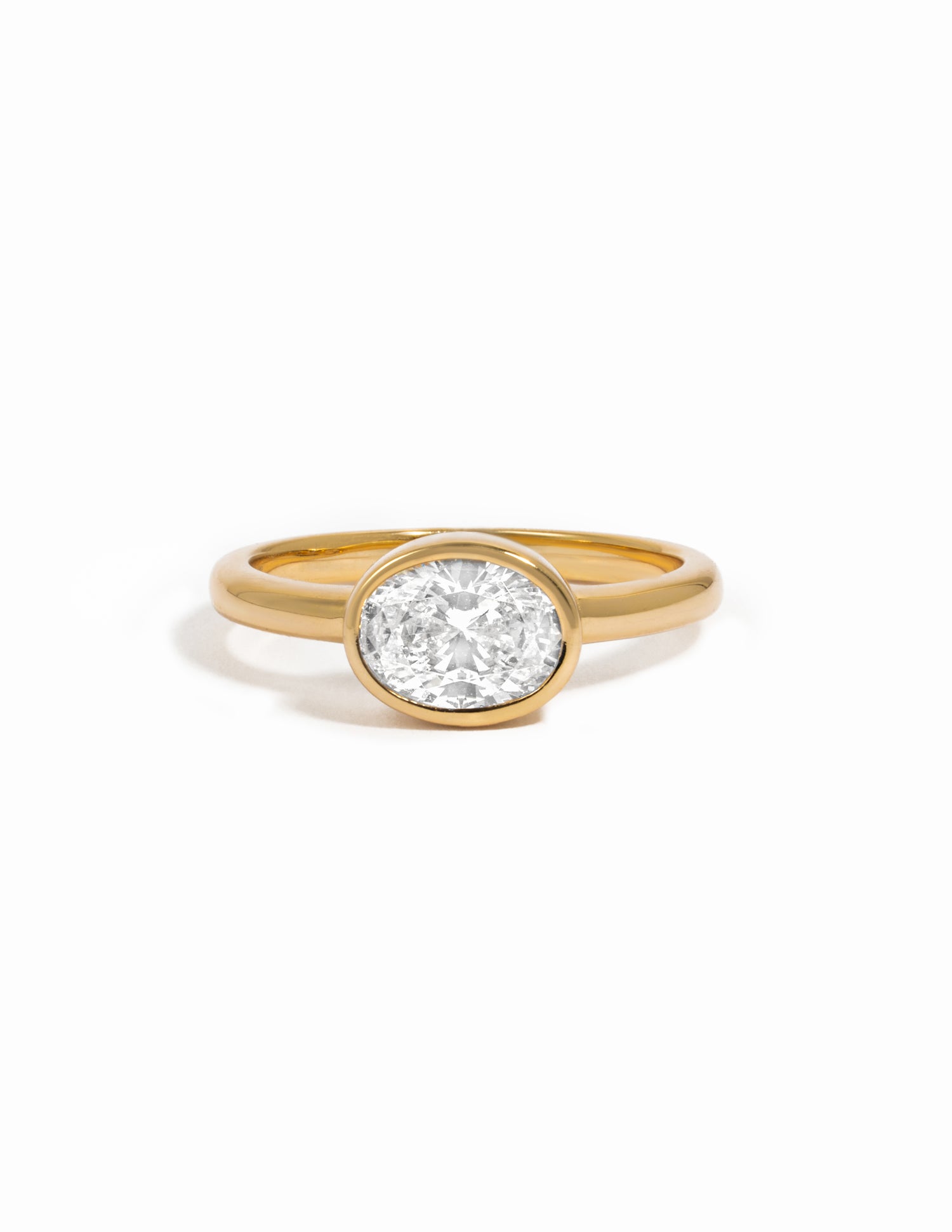 A yellow gold ring with a bezel-set oval cubic zirconia stone photographed on a clean white background.