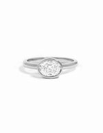 A silver-toned solitaire ring with an oval stone, set against a clean white background.