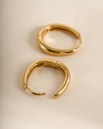 Close-up of gold oval hoop earrings by Sami Jewels, showcasing their smooth, elegant design and shiny finish.