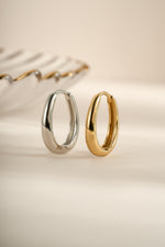 Sterling silver and gold oval hoop earrings by Sami Jewels, showcasing sleek and elegant jewelry design.