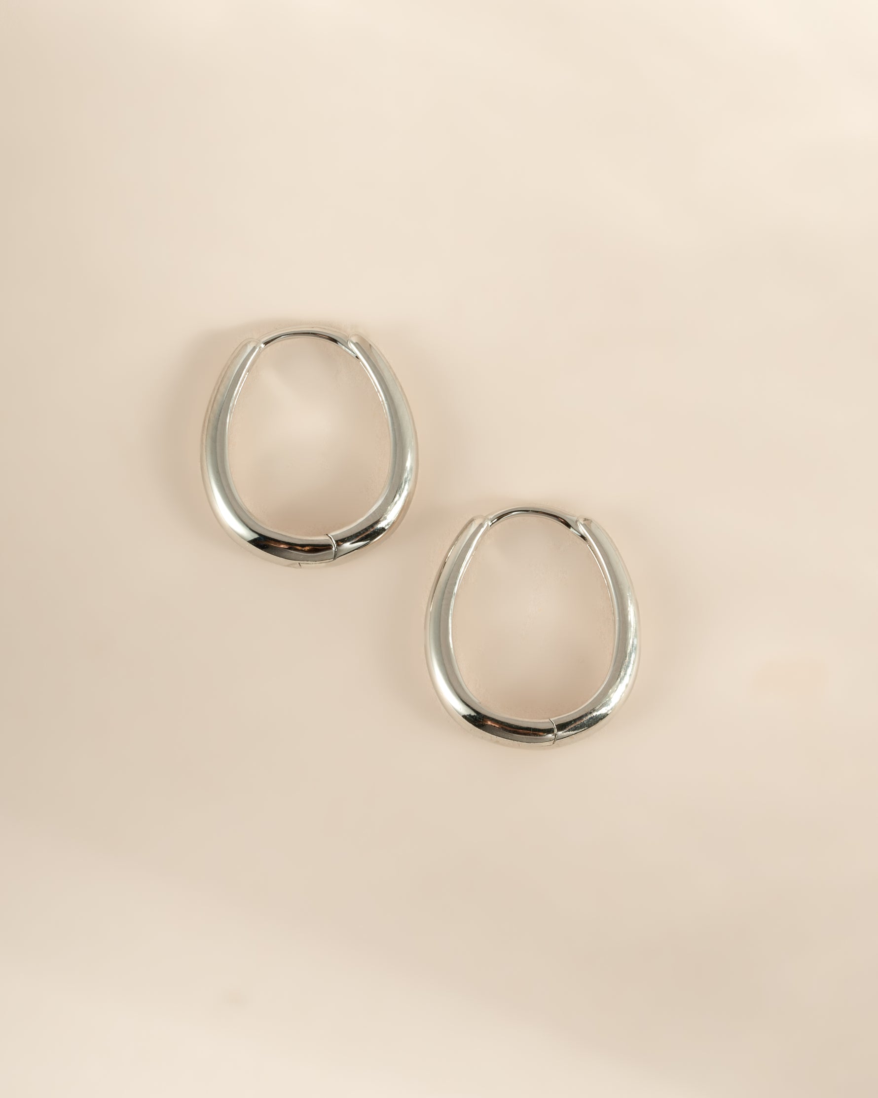 Sterling silver oval hoop earrings by Sami Jewels, shown in a side profile view highlighting their smooth, polished finish.