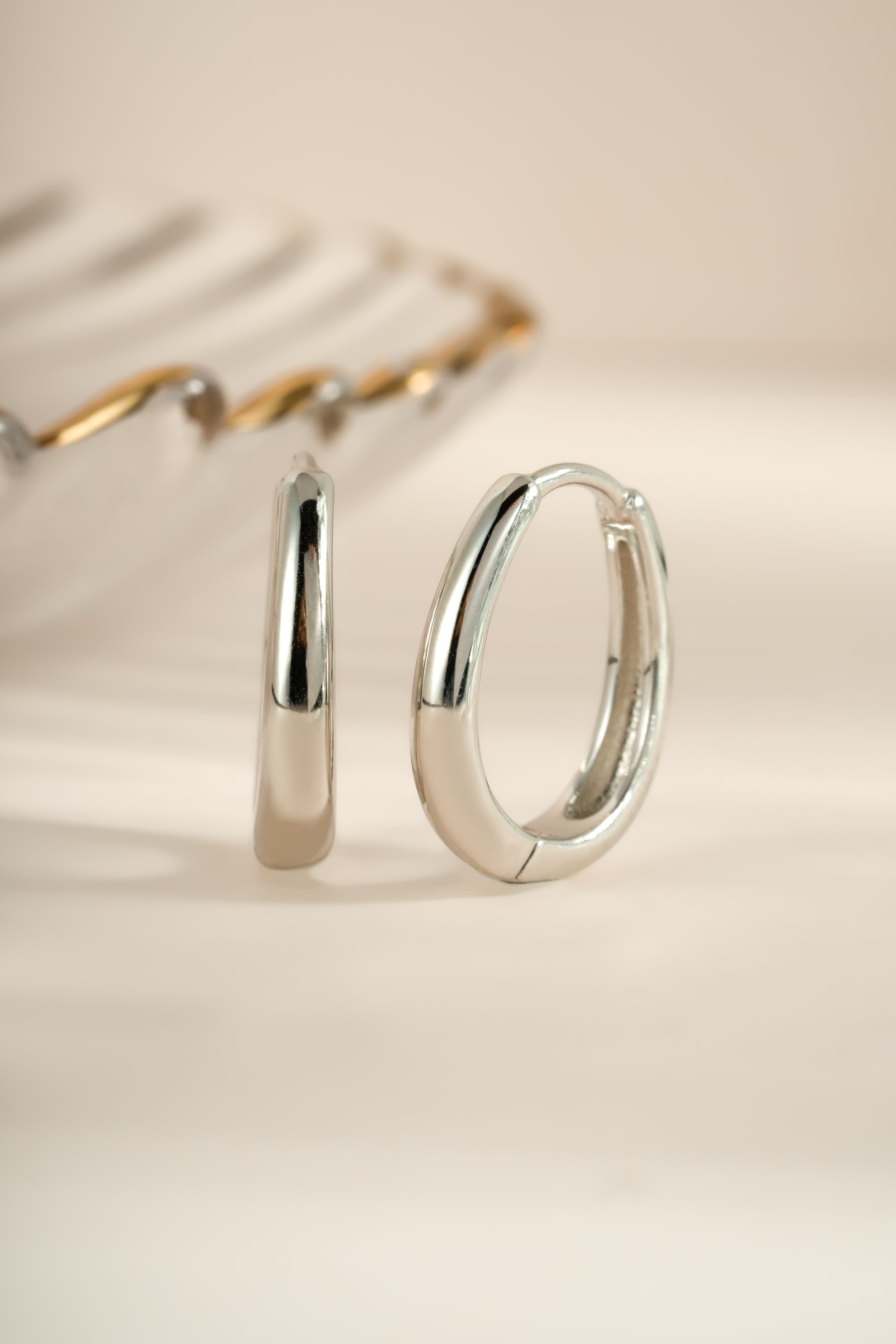 Sterling silver oval hoop earrings by Sami Jewels, showcasing smooth, polished design with a classic hoop shape.