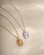 Gold and sterling silver oval medallion necklace by Sami Jewels featuring a detailed engraved pendant on a chain.
