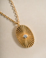 Close-up of a gold oval medallion necklace from Sami Jewels showing intricate design and polished finish.
