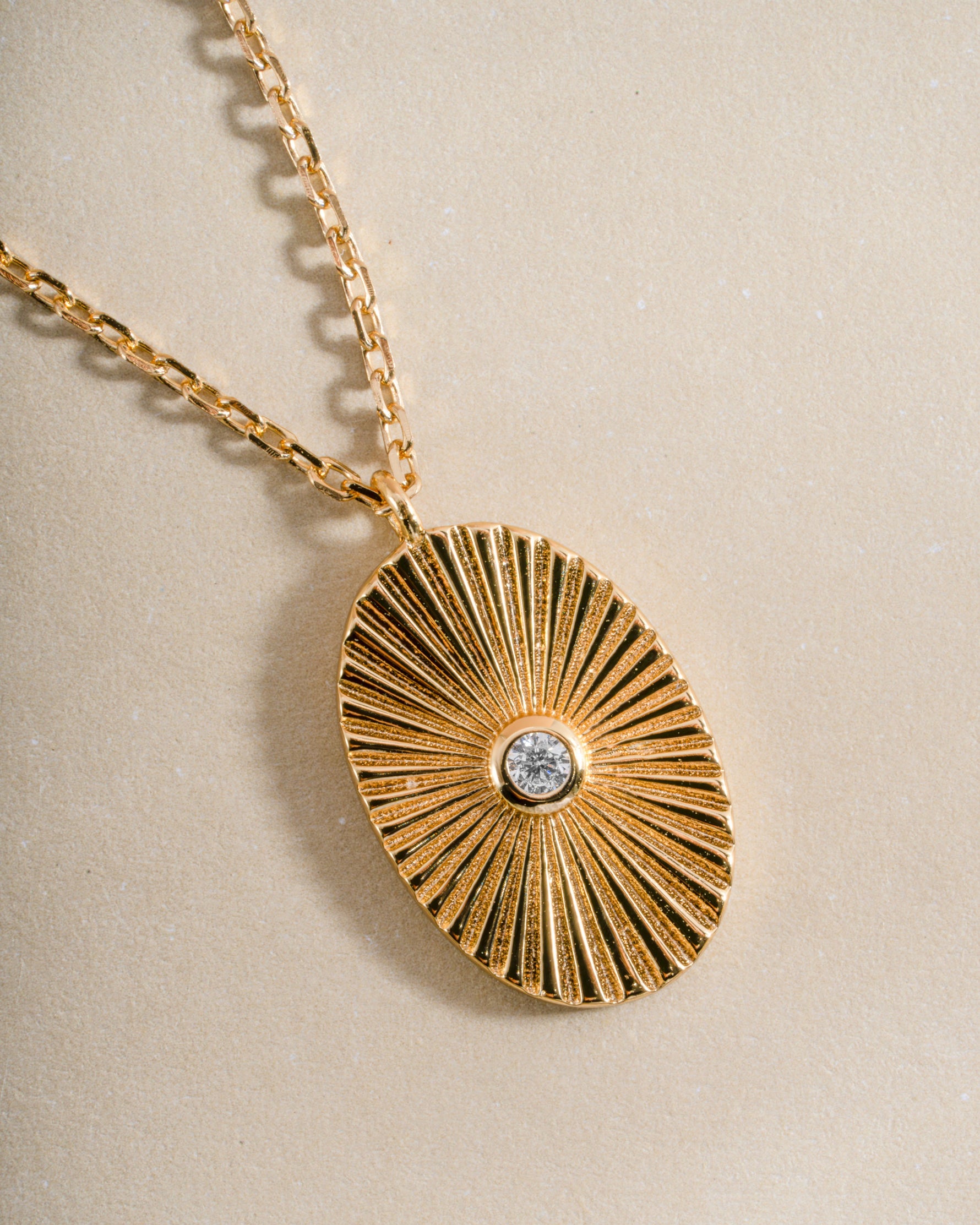 Close-up of a gold oval medallion necklace from Sami Jewels showing intricate design and polished finish.