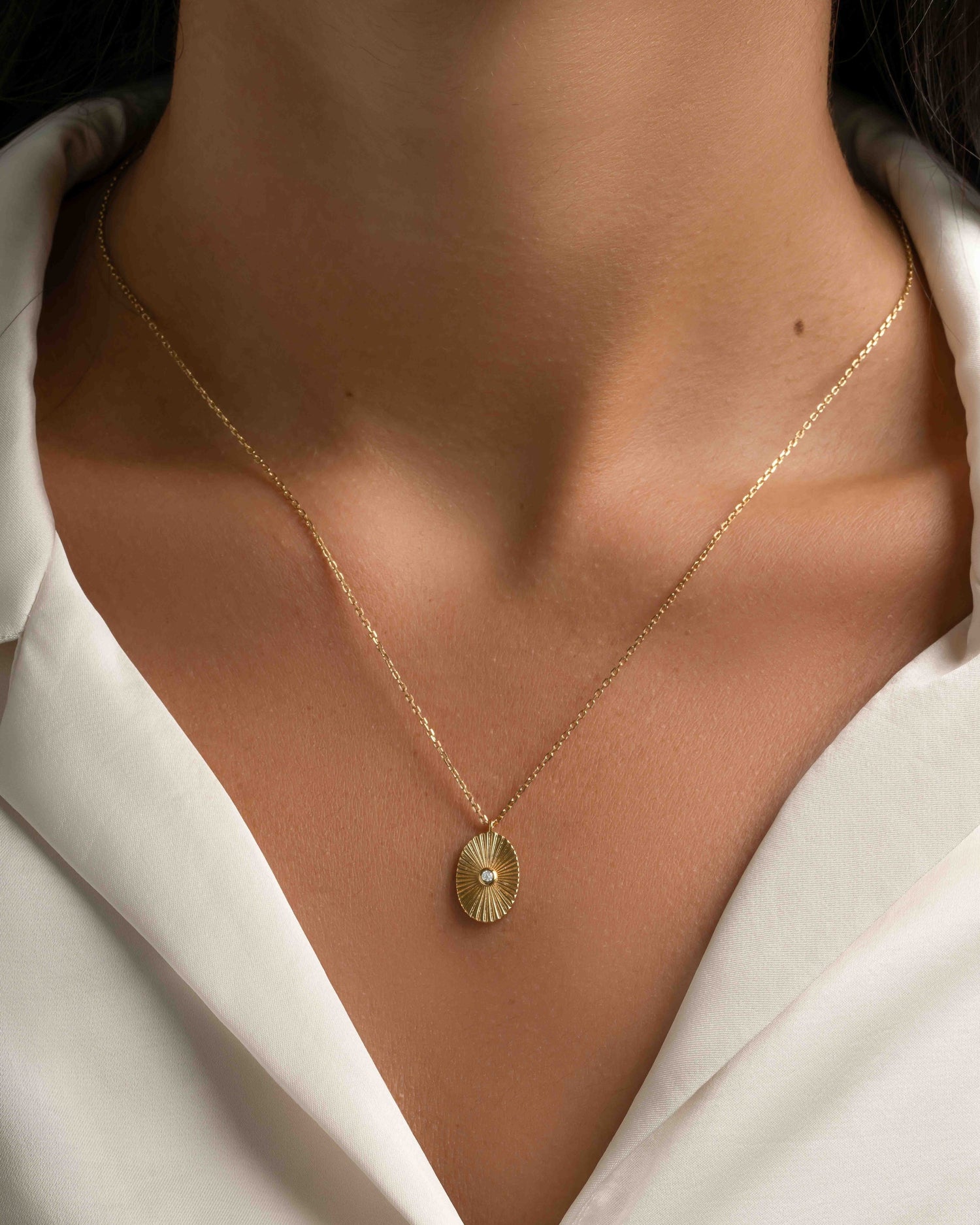 Gold oval medallion necklace by Sami Jewels worn on a model, showcasing a sleek, elegant jewelry piece.