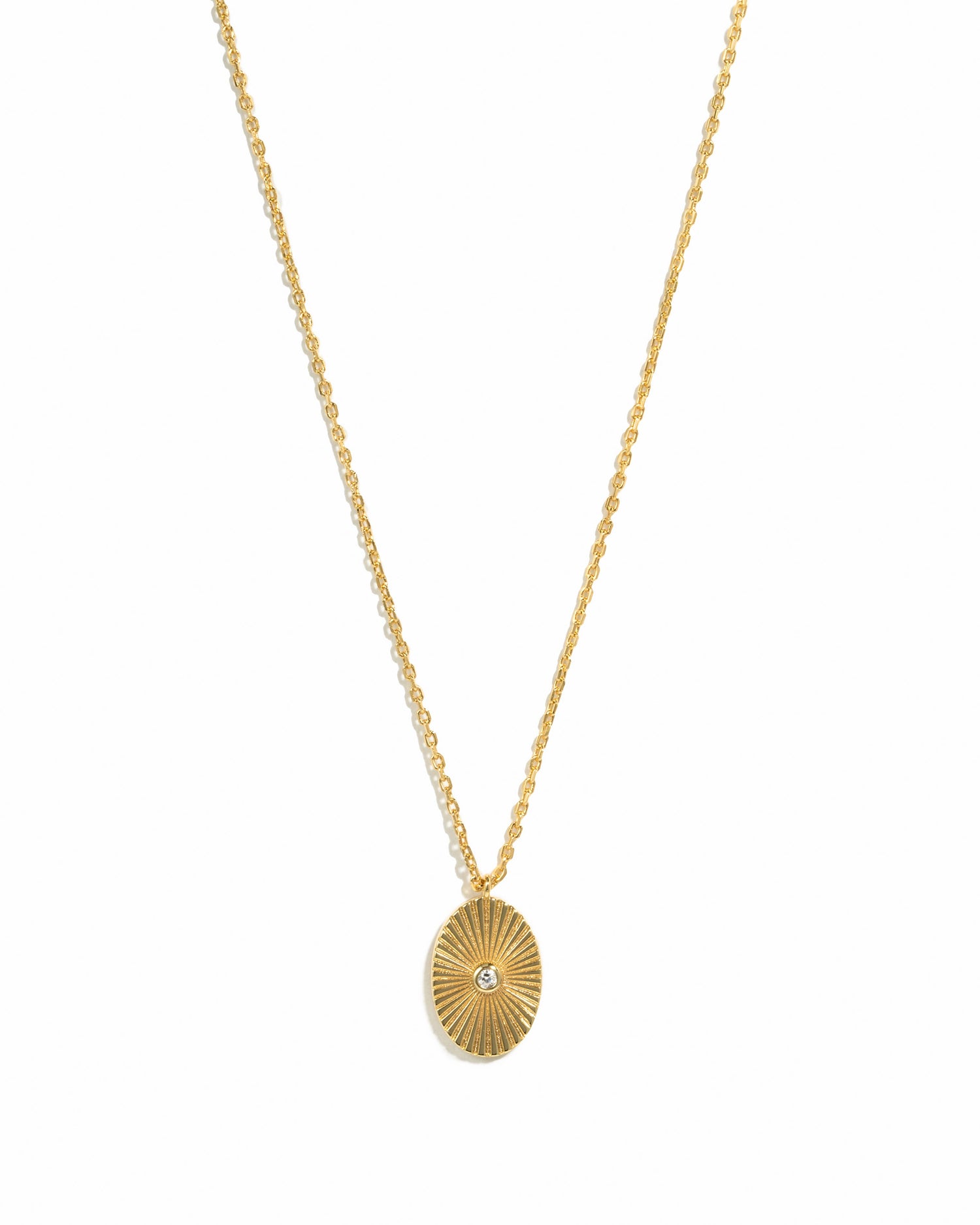 Gold oval medallion necklace by Sami Jewels displayed against a white background, showcasing its elegant design and polished finish.