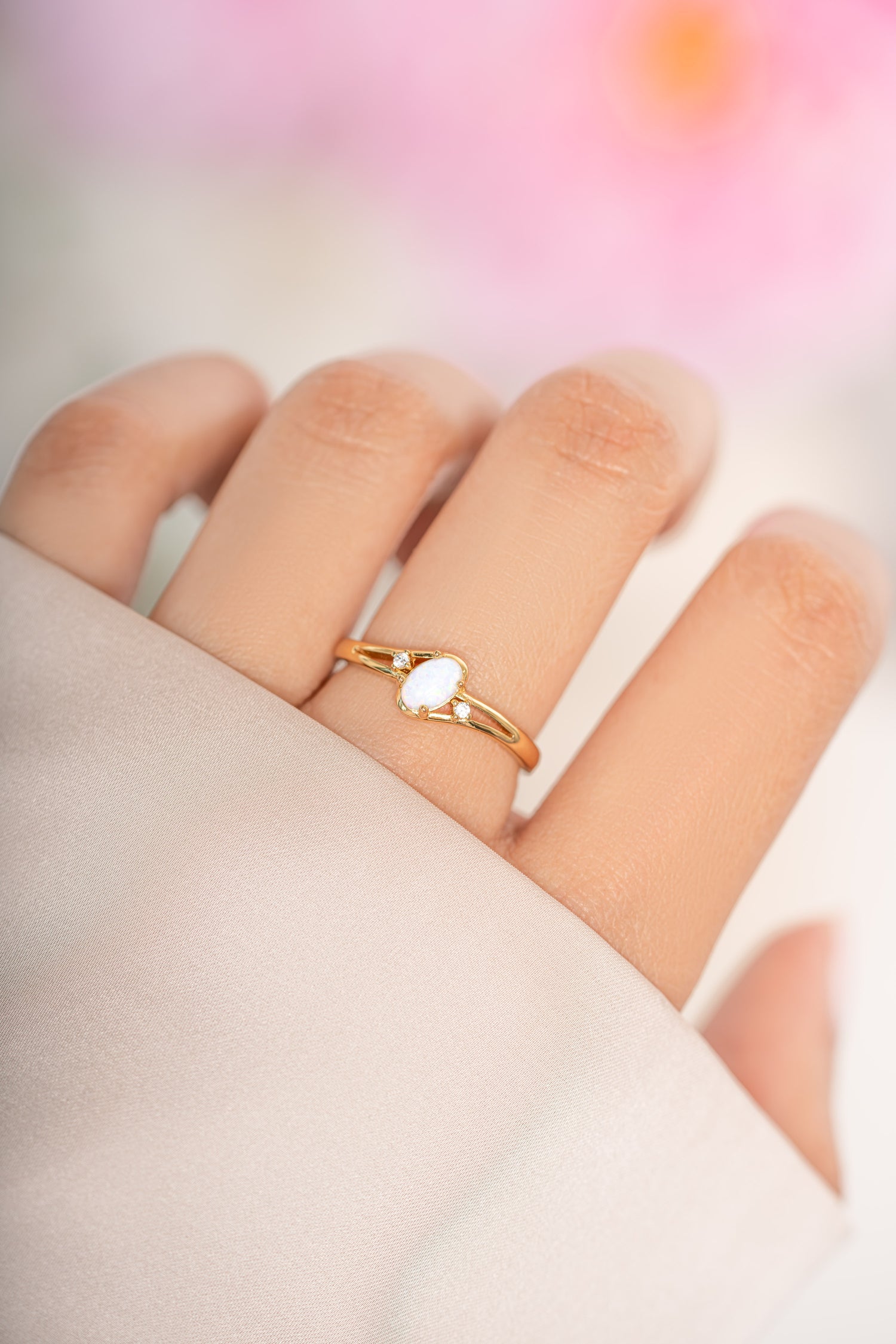 Small oval opal ring by Sami Jewels with a gold band, showcasing the elegant oval-shaped opal gemstone on a model.