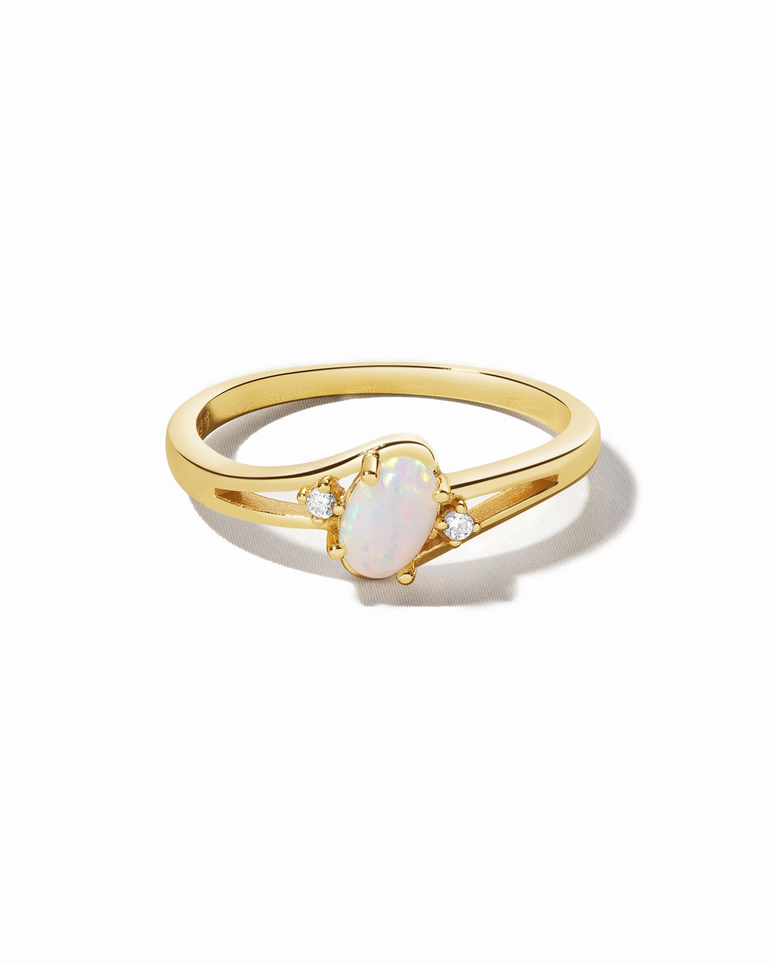 Small oval opal ring by Sami Jewels featuring a gold band and a vibrant white opal gemstone on a white background.