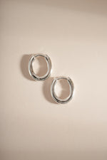 Sterling silver oval plain huggie earrings by Sami Jewels, close-up view showing smooth, minimalist hoop design.