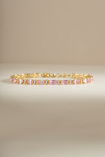 A gold bracelet featuring a row of alternating pink oval gemstones and white round diamonds.