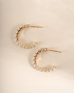 Gold oval studded hoop earrings by Sami Jewels, side profile showing textured surface and classic hoop shape.