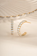 Gold oval studded hoop earrings from Sami Jewels featuring a sleek, modern design with embedded stones.