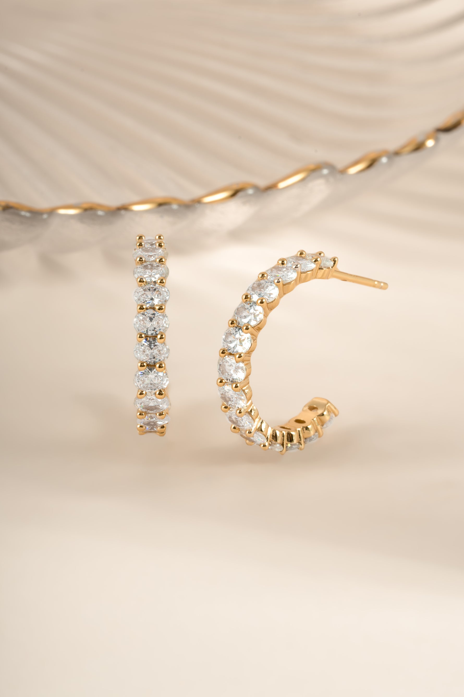 Gold oval studded hoop earrings from Sami Jewels featuring a sleek, modern design with embedded stones.