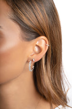 Sterling silver oval studded hoop earrings by Sami Jewels displayed on a model.