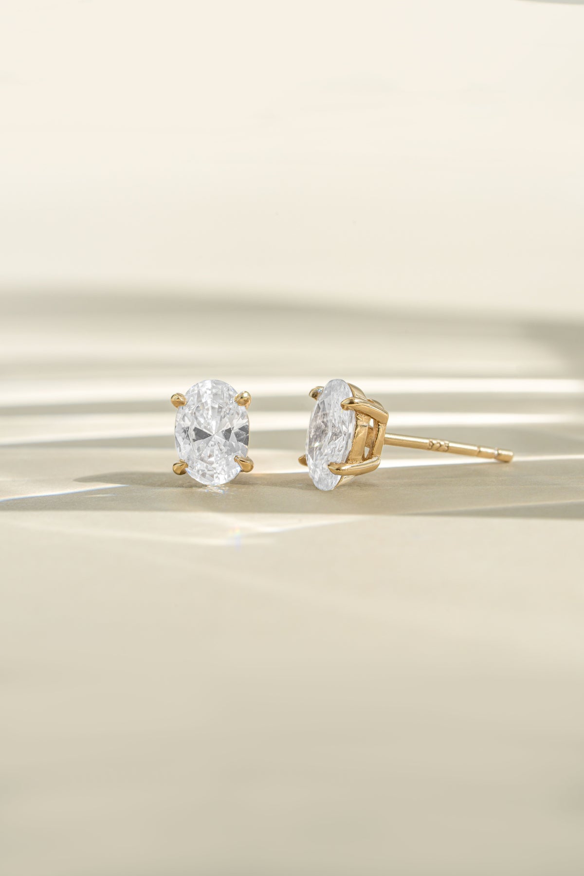 Gold 4x6mm oval studs shown from the front and side with sunlight across the display.